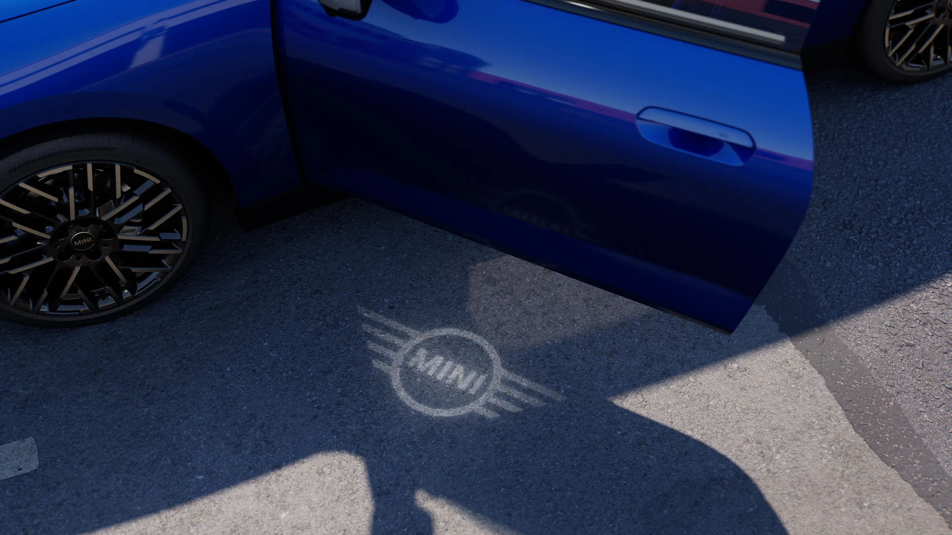 Vista esterna di una MINI Cooper 100% elettrica con portiera aperta e luce di benvenuto con logo MINI proiettata a terra