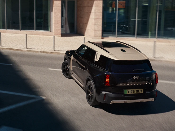 Vista posteriore dall'alto di MINI Countryman 100% elettrica in Midnight Black con tetto Vibrant Silver parcheggiata