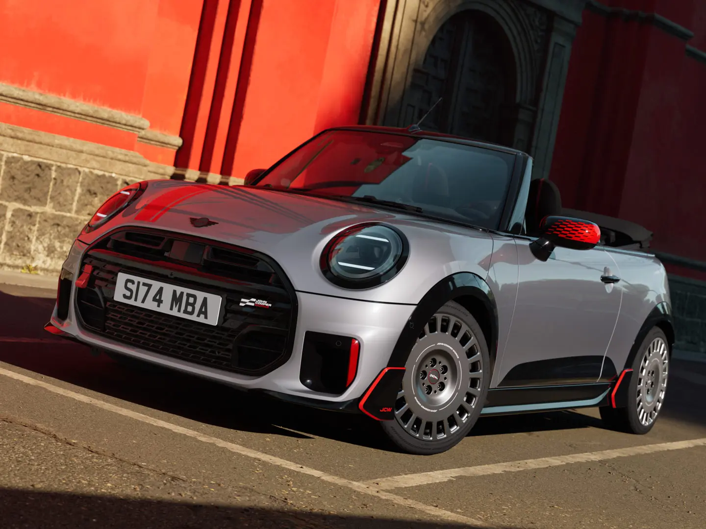MINI Cabrio di colore argento con elementi stilistici sportivi JCW, tra cui calotte degli specchietti MINI JCW, strisce sportive e winglet.