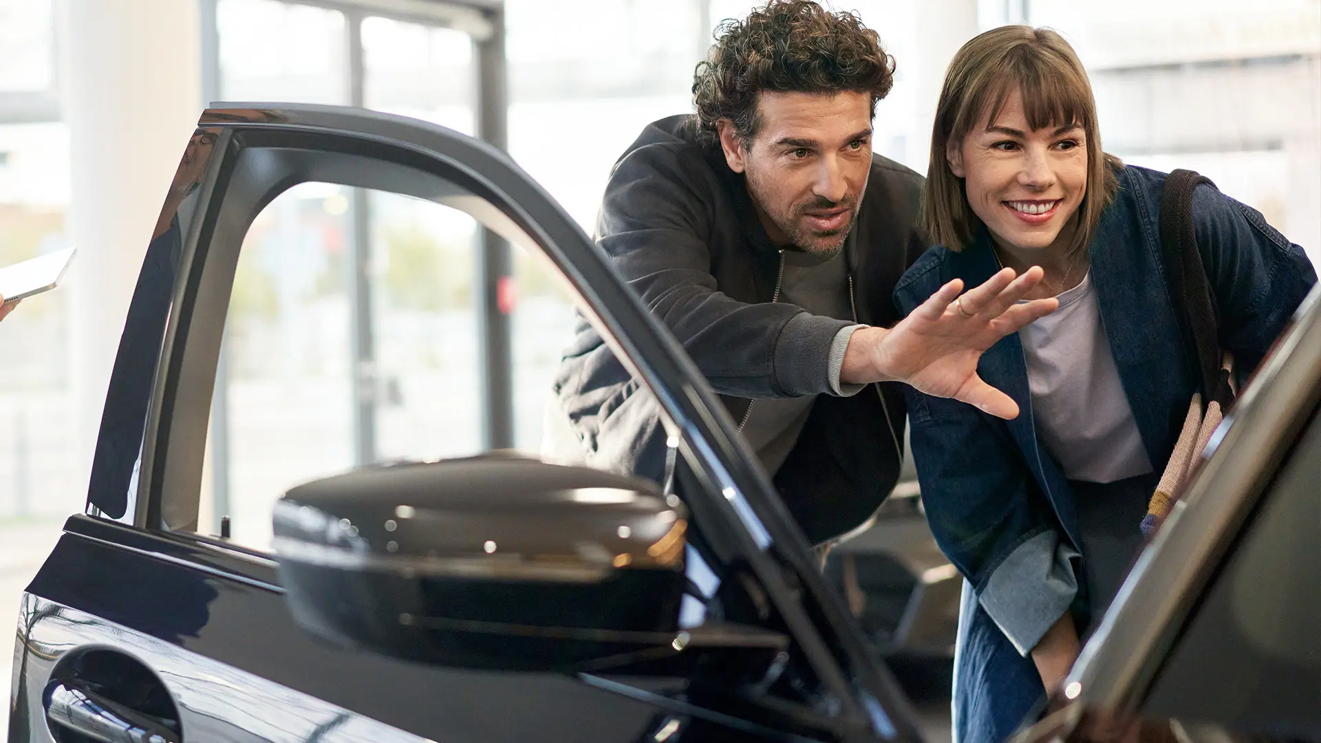 MINI all’interno di un concessionario MINI insieme a un consulente mentre consiglia il cliente e illustra le caratteristiche dell’abitacolo.