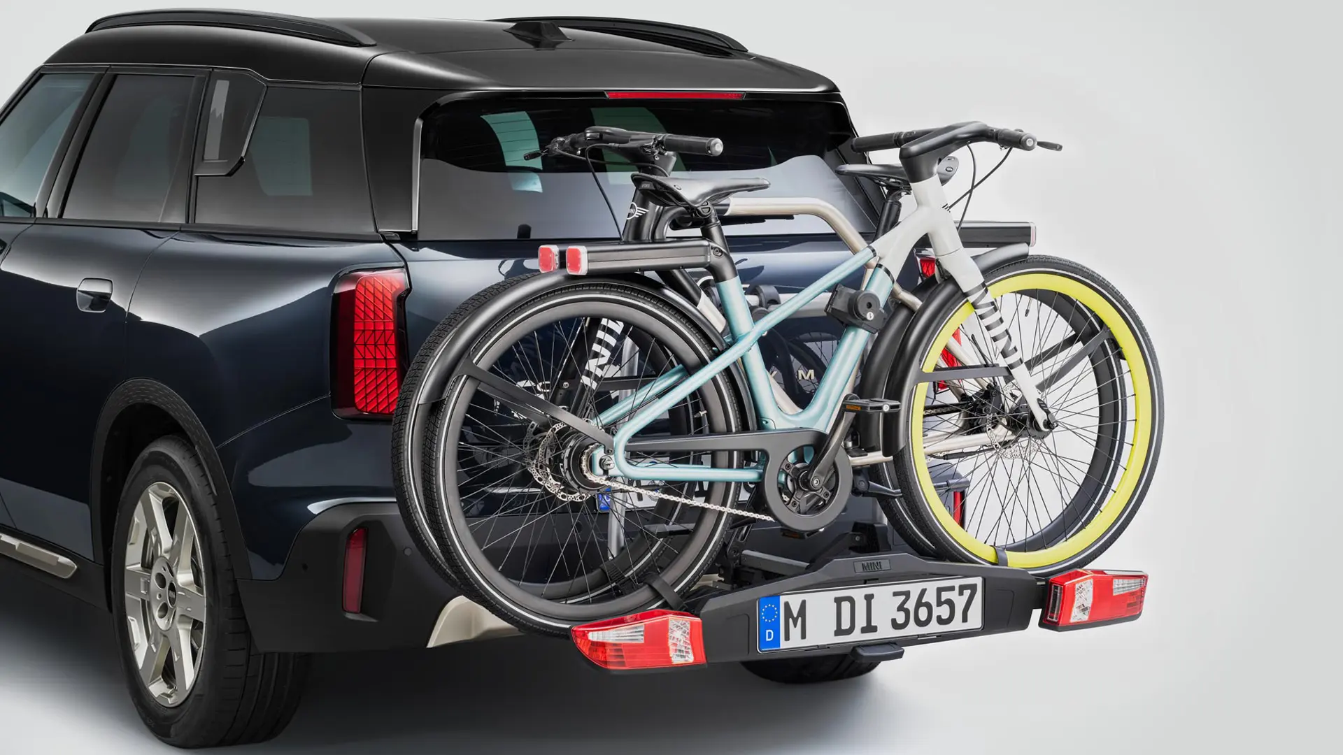 MINI Countryman in nero con portabici posteriore occupato da due mountain bike, vista posteriore.