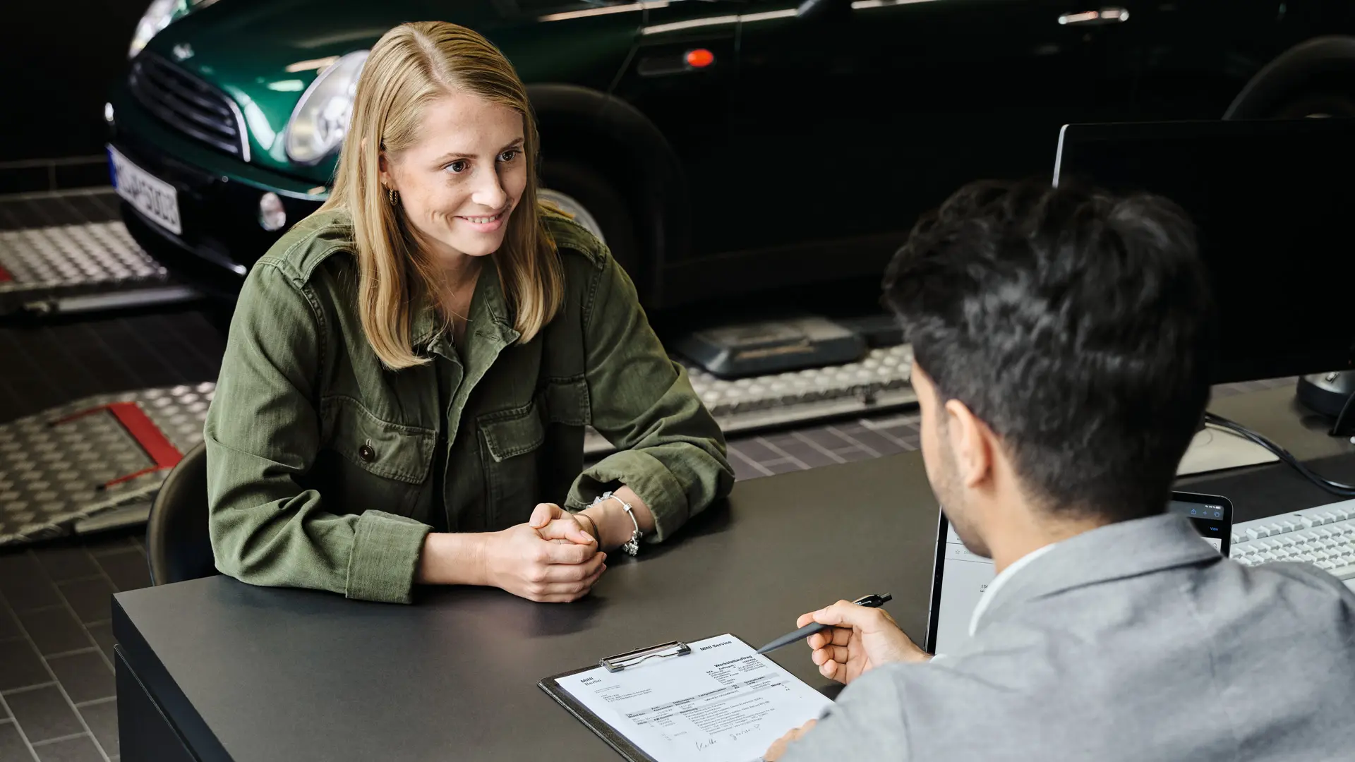 Centro MINI con consulente mentre fornisce informazioni alla cliente sulle opzioni di service disponibili, entrambi seduti a un tavolo.