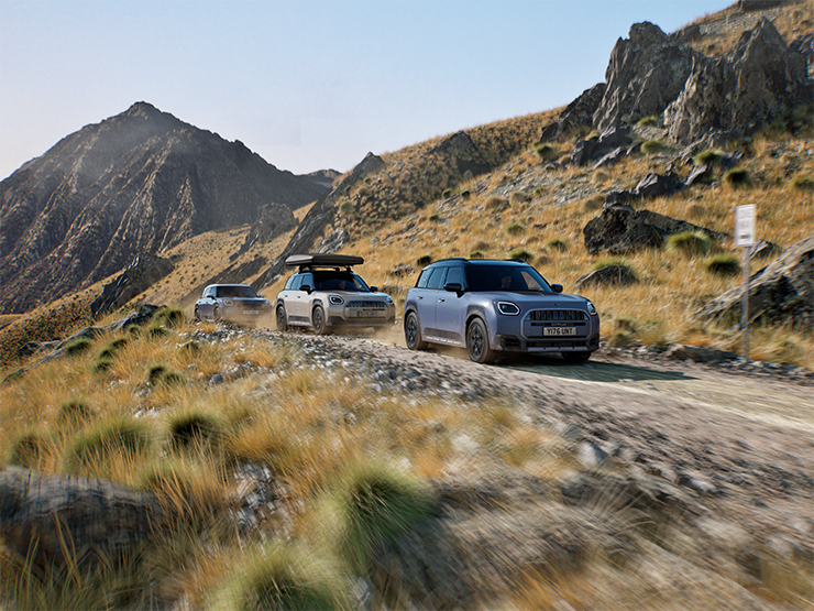 Immagine di più modelli MINI Countryman Untamed Edition che percorrono una strada di montagna fuoristrada.