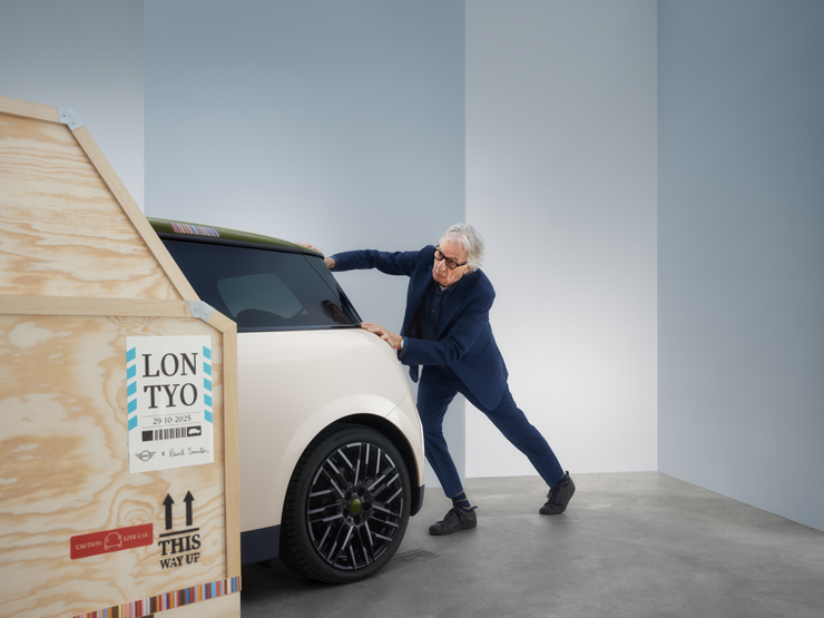 Vista posteriore della MINI Cooper Paul Smith Edition 100% elettrica in Inspired White con Paul Smith dietro la vettura